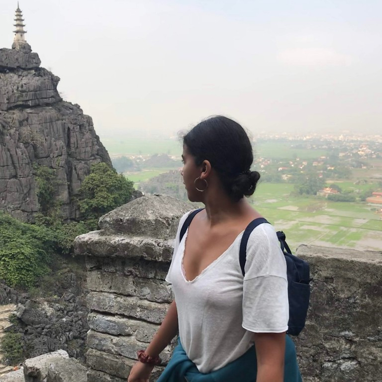 HIEP recipients in Asia and the Middle East - Robiati Endashaw poses for a photo overlooking a steep cliff in Hanoi with a mountain and temple in the background.