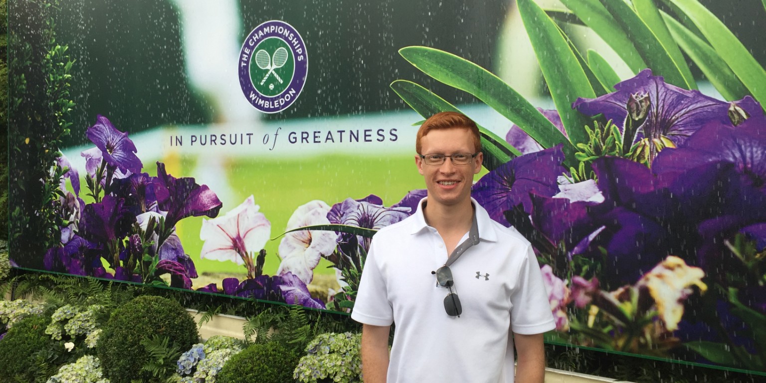 HIEP students in the UK - Joshua Zaacks poses for a photo in front a Wimbledon billboard in London