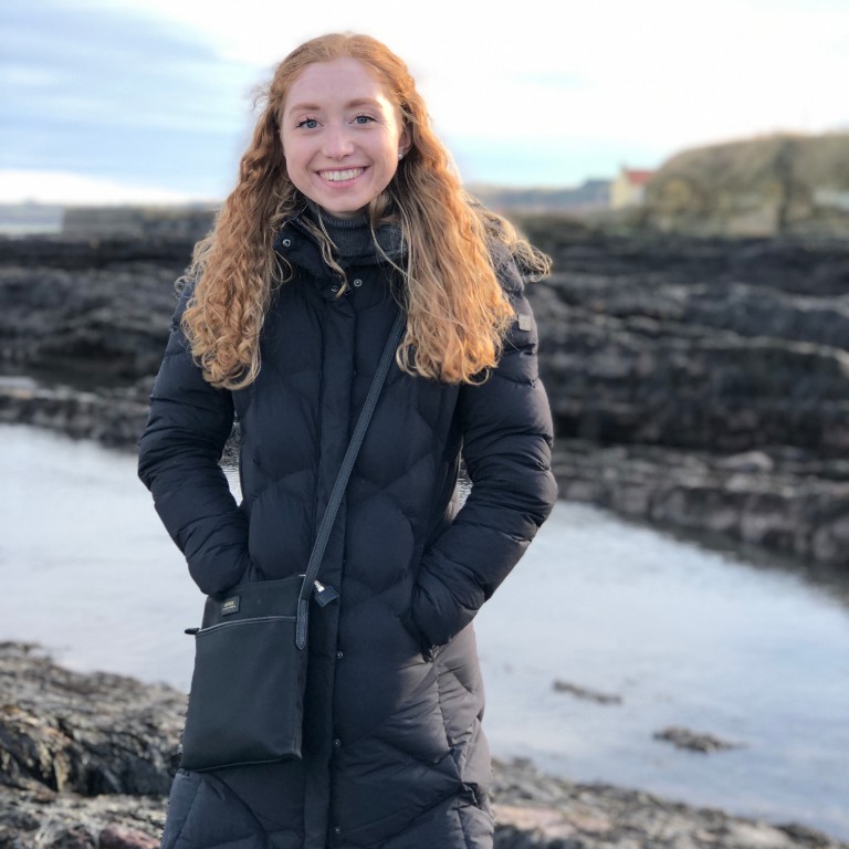 HIEP students in the UK - Corinne Maue poses for a photo in a winter coat at the beaches of St. Andrews in Scotland
